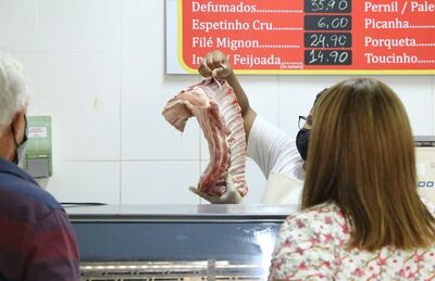 Consumidores observam peça de carne em açougue de Campo Grande 
