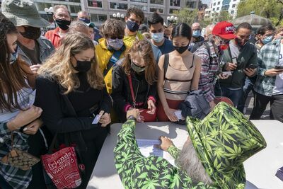 Homem com fantasia de cannabis distribui cigarros de maconha durante o evento 