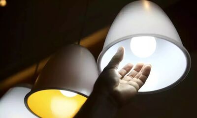 Homem confere lâmpada: custo extra da energia se manterá em patamar alto.