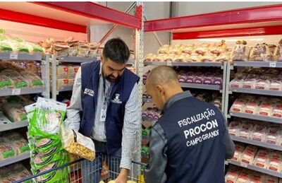 Fiscais descartando os produtos irregulares encontrados no supermercado