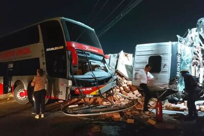 Ônibus de turismo e caminhão com tijolos na pista após batida.
