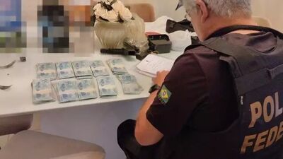 Policial federal contando dinheiro encontrado com investigados. (Foto: Divulgação PF)