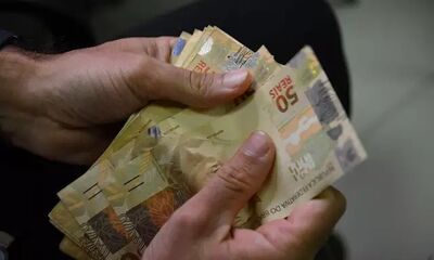 Cidadão faz a contagem de cédulas de R$ 50.
