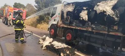 Caminhão destruído por incêndio e bombeiros no combate ao fogo. 