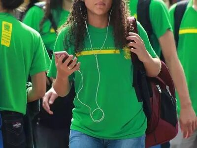 Aluna da rede estadual de ensino utiliza celular na saída da escola. 