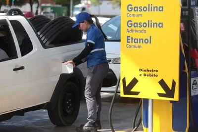 Frentista abastecendo veículo em posto de combustível.