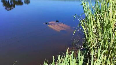 Veículo Gol submerso na lagoa após acidente.