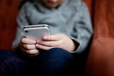 Criança no celular. Foto: Canva