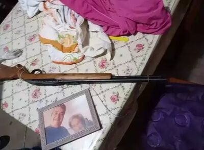 Arma usada no crime ao lado de foto do casal em cima da mesa. Foto: Direto das Ruas
