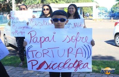 Criança segura cartaz com a frase: Papai sofre tortura psicológica