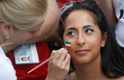 Mulher pinta rosto de torcedora iraniana em estádio de São Petersburgo durante jogo entre Irã e Marrocos na Copa do Mundo da Rússia, na sexta-feira (15)