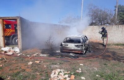 Bombeiro fazendo trabalho de rescaldo em veículo queimado em terreno