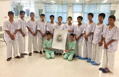 No Hospital Chiang Rai Prachanukroh, em Chiang Rai, os 12 meninos resgatados posam para foto com um desenho de Samarn Kunan, ex-mergulhador da Marinha tailandesa que morreu trabalhando para resgatá-los