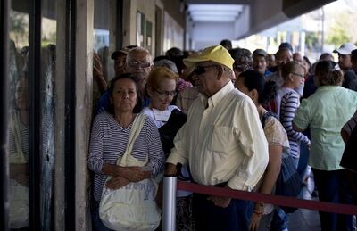 Clientes fazem fila do lado de fora de agência bancária em Maracaibo, na Venezuela, para obter notas da nova moeda