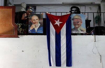 Bandeira de Cuba é clicada pendurada ao lado de fotografias de Raúl e Fidel Castro
