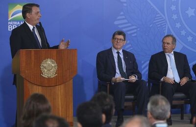 O presidente Jair Bolsonaro durante discurso no Palácio do Planalto, diante do presidente do BNDES, Joaquim Levy, e do ministro da Economia, Paulo Guedes