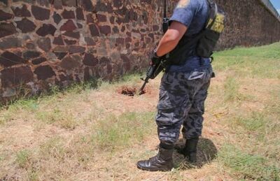 Agente de segurança paraguaio próximo a buraco que precisos fizeram em presídio na fronteira.