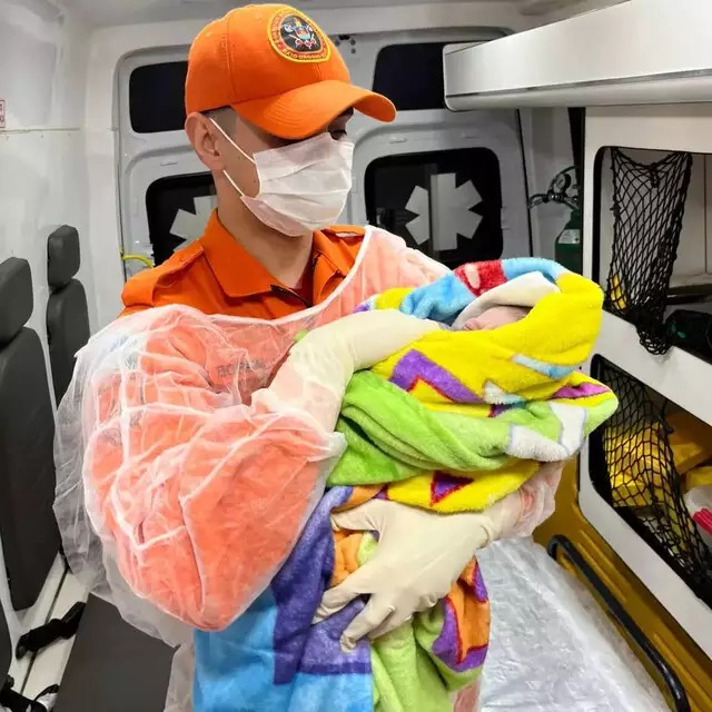 Bombeiro segura bebê enrolado em cobertor dentro da ambulância. Foto: Divulgação/Corpo de Bombeiros